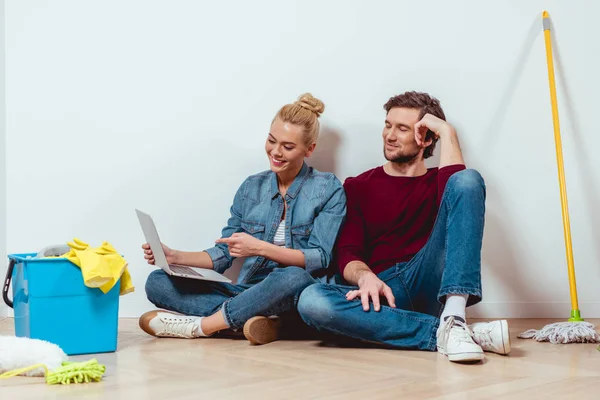 Smiling Girl Sitting Floor Husband Pointing Finger Laptop Screen — Free Stock Photo