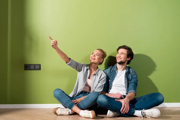 Handsome Man Sitting Floor Smiling Girl Pointing Finger Apartment — Stock Photo, Image