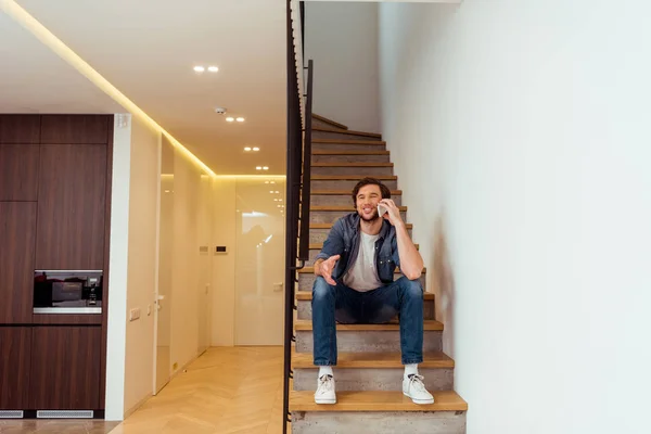 Улыбающийся Мужчина Сидит Лестнице Разговаривает Смартфоне — Бесплатное стоковое фото