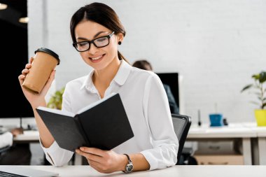 Genç işkadını gözlük ile kahve ve işyerinde ofiste dizüstü