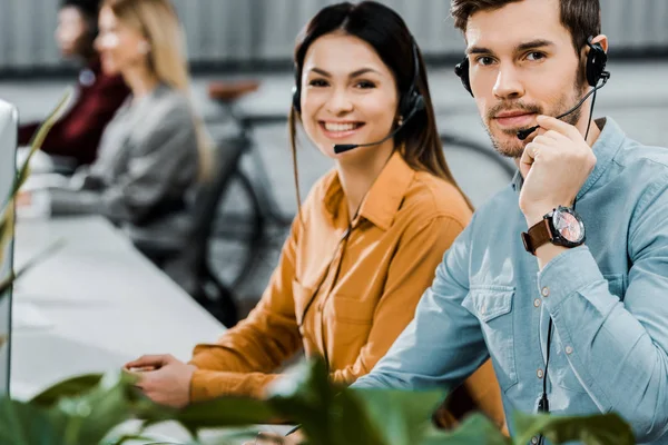 Glimlachend Call Center Exploitanten Hoofdtelefoons Kijken Camera Kantoor — Stockfoto