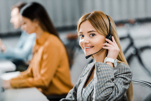 selective focus of smiling call center operator looking at camera in office