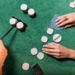 Обрезанный образ женщины и крупье, играющих в покер за столом в казино