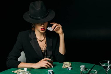 Casino masada çekici kız ceket ve şapka tutan bardak viski ve poker fişleri