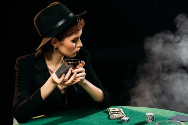 uzak seyir çekici kız ceket ve Casino, masada poker oynarken bardak viski holding şapkası