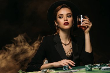 çekici kız ceket ve casino ve uzak arıyor poker masasında bardak viski holding şapkası