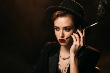 çekici kız ceket ve şapka duman sigara siyah ve uzağa arıyorsunuz