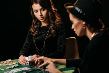 Casino karanlık odada masada poker oynamaya çekici kızlar