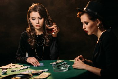 Casino, bardak viski tutan kadın masada poker oynamaya çekici kızlar