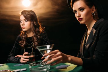 Casino, kokteyl bardak tutan kadın masada poker oynamaya çekici kızlar