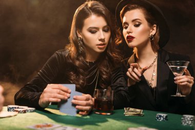 Casino, arkadaşına bir şeye işaret eden kadın masada poker oynamaya çekici kızlar