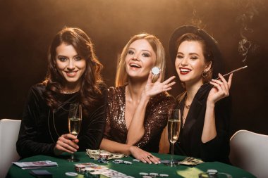 Şampanya, çekici kızlar sigara ve poker chips Casino masada oturan gülüyor