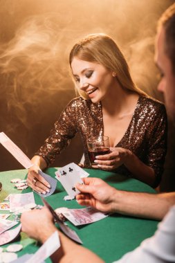 Casino, euro banknot masaya düşen krupiye ile poker oynamaya gülümseyen çekici kız