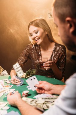 Casino, masanın üstüne düşen doları banknot krupiye poker oynarken mutlu güzel kız