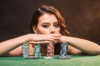 poker fişi eğilerek ve siyahta izole kamera bakıyor güzel kahverengi saçlı kız