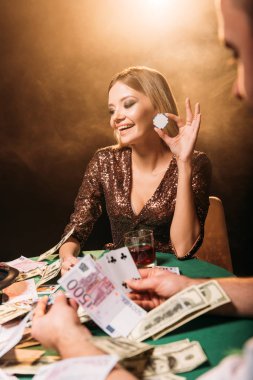 Krupiye poker oynuyor ve casino poker chip tutan mutlu çekici kız