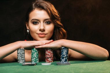 poker fişi eğilerek ve siyahta izole kamera bakarak çekici kahverengi saçlı kız