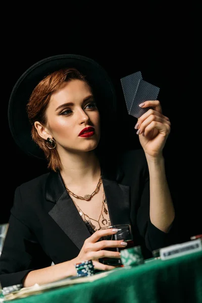 ジャケットや帽子ウィスキーのグラスを押しながらカジノでポーカーをプレーで美しい少女の液面 — ストック写真