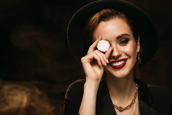 Счастливая Привлекательная Девушка Куртке Шляпе Покрывая Глаз Фишкой Покера Глядя — стоковое фото