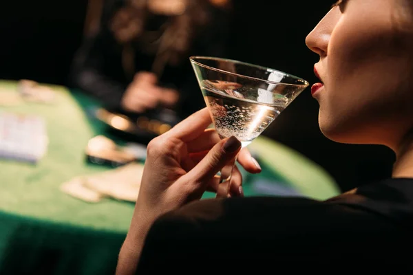 在赌场的桌子上玩扑克时 女孩喝鸡尾酒的裁剪图像 — 图库照片