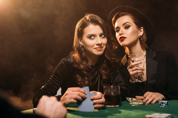 cheerful attractive girls playing poker at table in casino