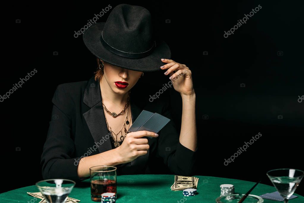 Attractive girl in jacket and hat playing poker in casino