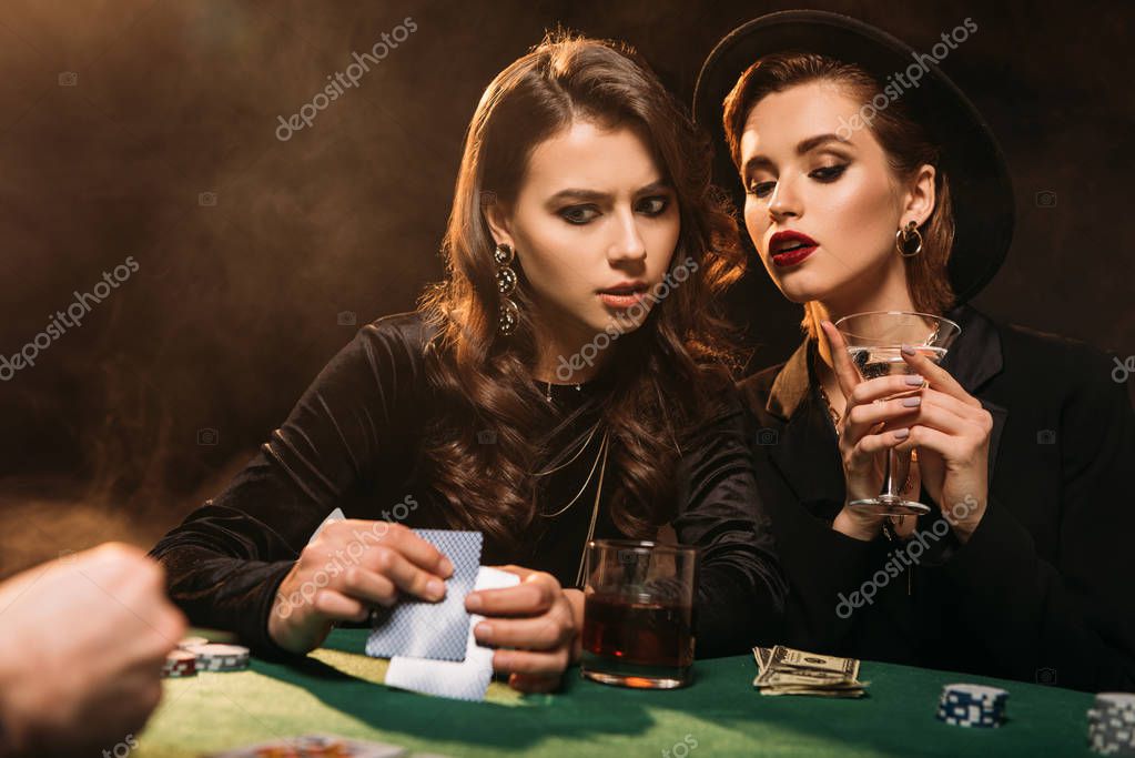 Serious attractive girls playing poker at table in casino