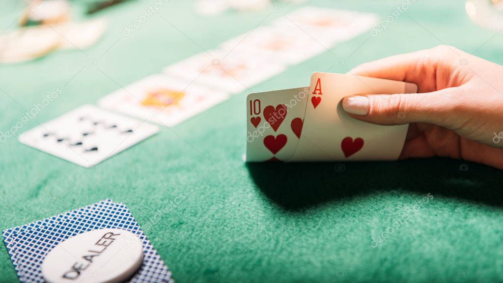 cropped image of girl playing poker and holding cards in casino