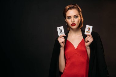 güzel kız kırmızı elbise ve siyah izole kamera bakıyor ve poker kartları tutarak siyah ceket