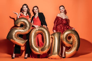 sürpriz çekici kızlar 2019 balonlar tutarak ve kameraya turuncu üzerinde seyir şık parti elbiseleri