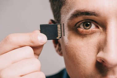selective focus of man holding microchip near head isolated on grey clipart