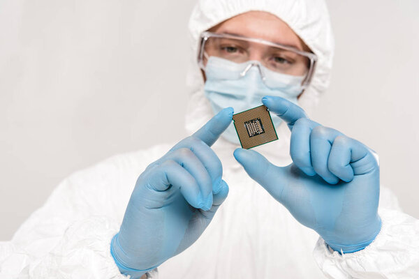 selective focus of microchip in hands of scientist wearing latex gloves and googles isolated on grey