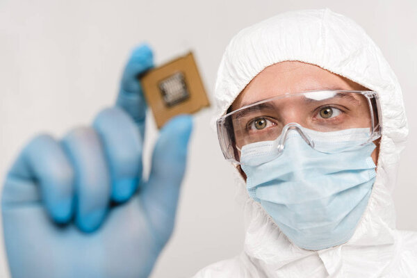 selective focus of scientist looking at microchip in latex glove isolated on grey