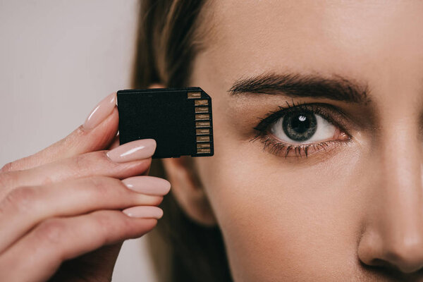 cropped view of woman holding microchip in hand near eye