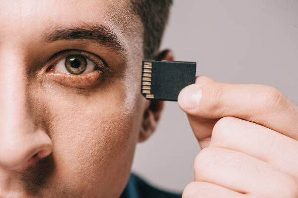 selective focus of man implanting microchip in head isolated on grey