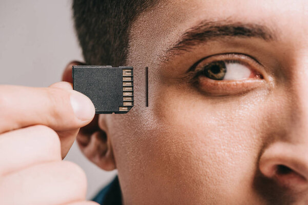 close up of man implanting microchip in head isolated on grey