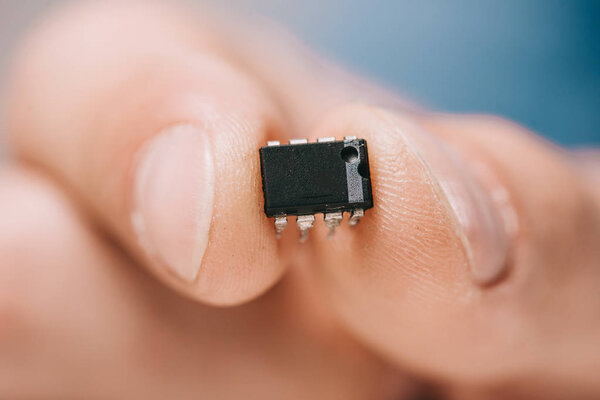 selective focus man showing black, metallic microchip 