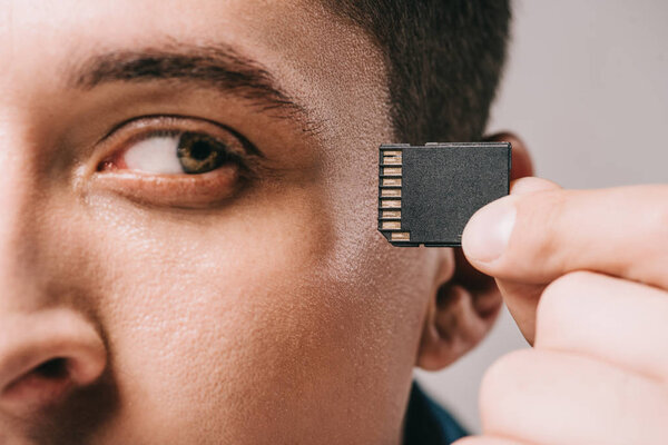 close up of man looking at chip near head isolated on grey
