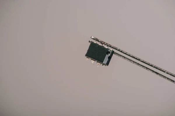 Metalik Gri Arka Plan Üzerinde Küçük Mikroçip Cımbızla — Stok fotoğraf