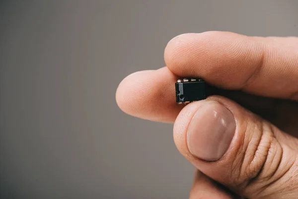 Mężczyzna Trzymając Małe Microchip Ręku Szarym Tle — Zdjęcie stockowe