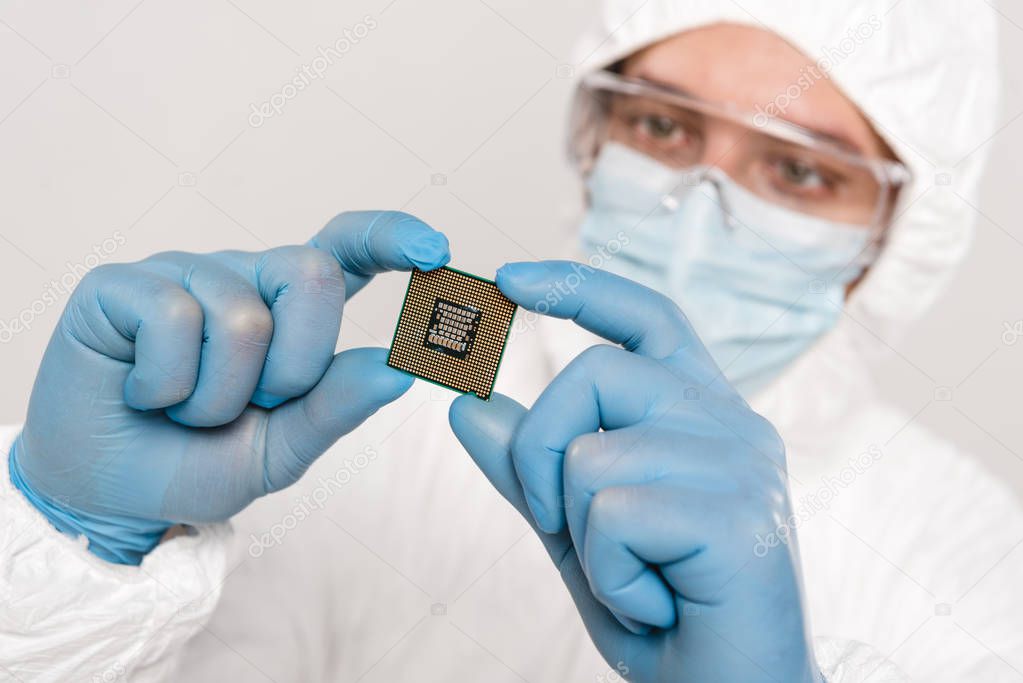 selective focus of microchip in hands of scientist wearing latex gloves isolated on grey