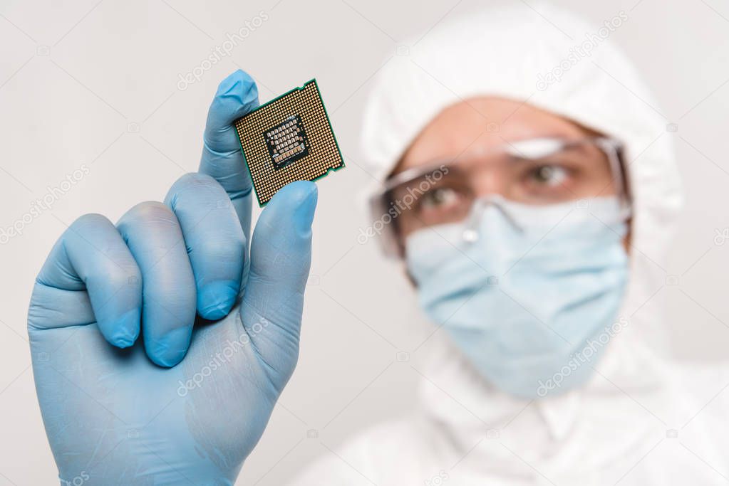 selective focus of microchip in hand of scientist wearing latex glove and googles isolated on grey