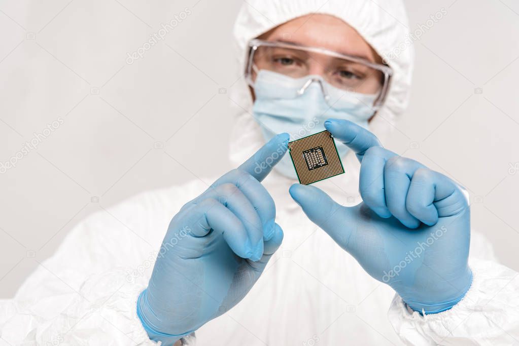 selective focus of microchip in hands of scientist wearing latex gloves and googles isolated on grey