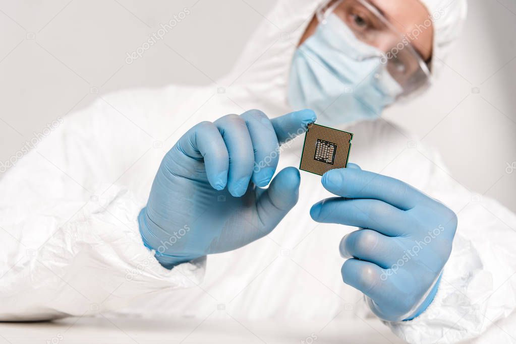 selective focus of microprocessor in hands of scientist in googles on grey background