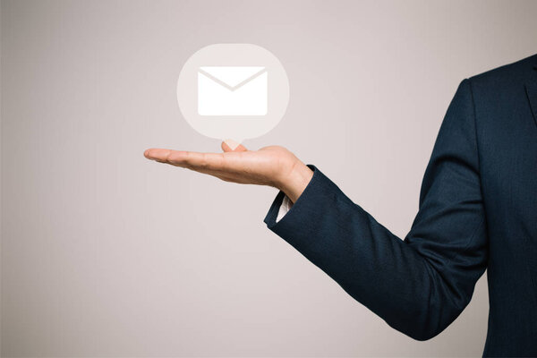 partial view of businessman in suit gesturing and presenting email icon isolated on grey