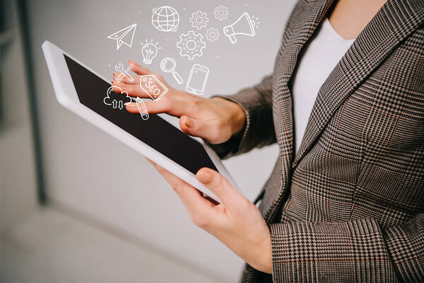 cropped view on businesswoman using and touching digital tablet with seo icons