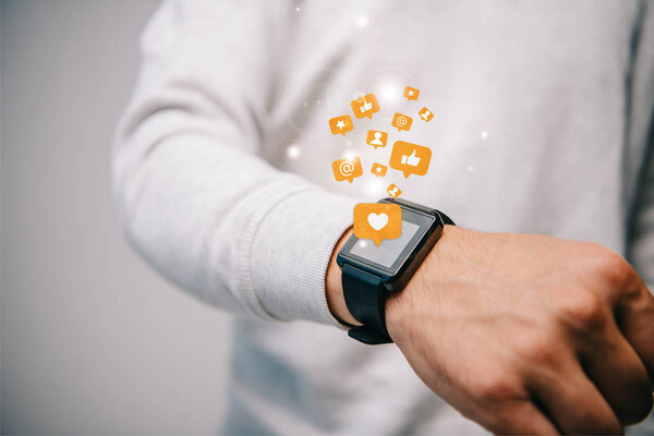 cropped view of man with smartwatch with multimedia icons