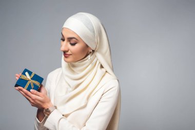 gülümseyen genç genç Müslüman kadın mevcut izole üzerinde gri holding 