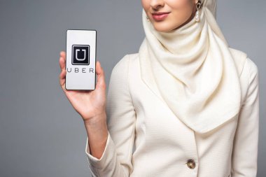 gri izole uber app ile smartphone tutan gülümseyen Müslüman kadın kırpılmış atış 