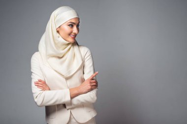 gülümseyen genç Müslüman kadın ile ayakta silah geçti ve seyir uzağa gri izole